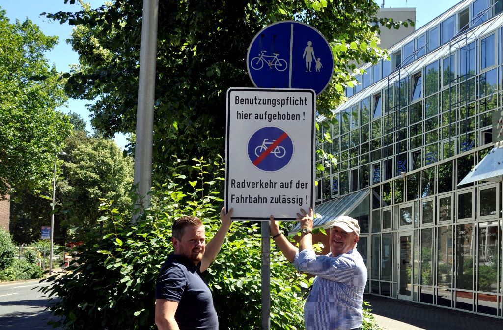 Fahrradbeauftragter Uwe Schmitz (rechts) und Mobilitätsmanager Benjamin Raßmanns mit einem Schild, das auf die Aufhebung der Radwegebenutzungspflicht hinweist. Foto: Stadt Düren