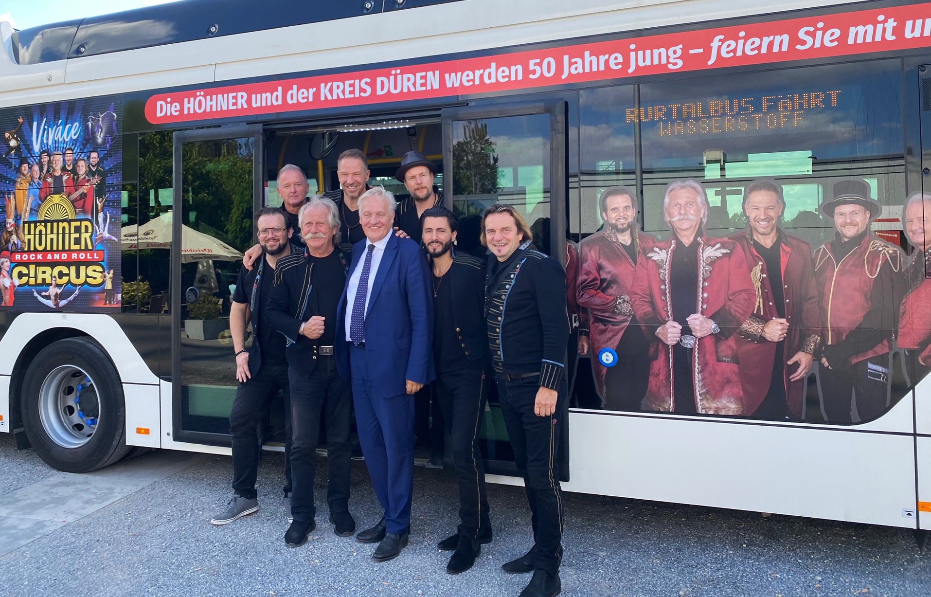 Landrat Wolfgang Spelthahn (vorne Mitte) und die Höhner stellen das Jubiläumsprogramm "Höhner Rock and Roll Circus" vor dem extra neu gestalteten Wasserstoffbus vor. Für Henning Krautmacher (vorne 2.v.l.) werden es die letzten Auftritte sein, denn er übergibt den Staffelstab an seinen Nachfolger Patrick Lück (hinten Mitte). Foto: Kreis Düren