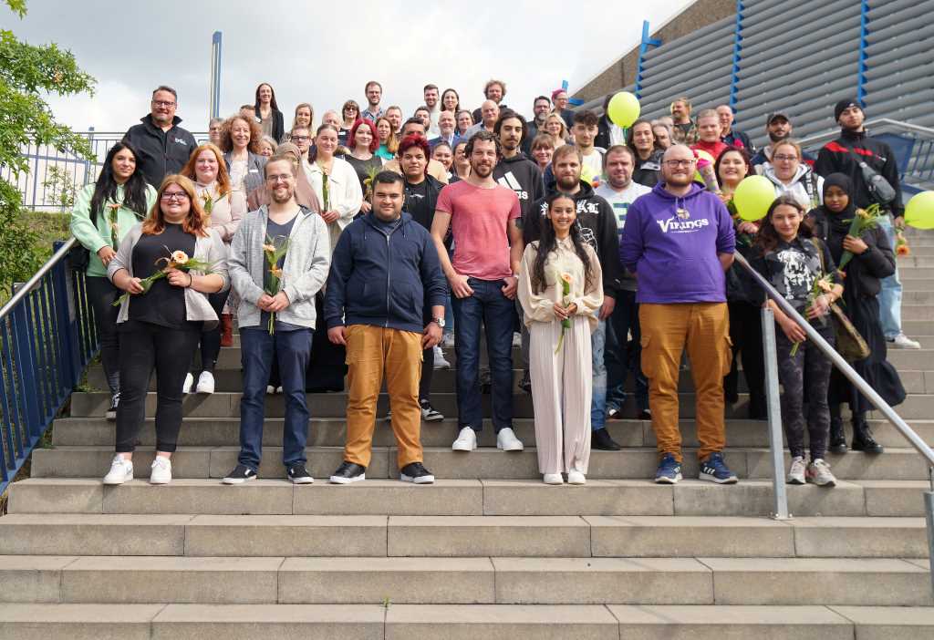 Die neuen Auszubildenden sowie die Verantwortlichen der Träger und des Kreises mit Landrat Wolfgang Spelthahn nach der Begrüßung auf der Außentreppe der Arena Kreis Düren. Foto: Kreis Düren