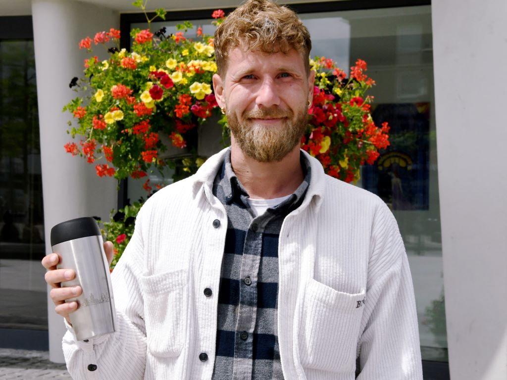 Simon Seifert, Klimaschutzmanager der Stadt Düren, genießt seinen Kaffee aus dem wiederverwendbaren Thermobecher der Stadt Düren.