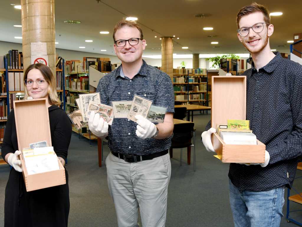 Der Leiter des Stadt- und Kreisarchivs Düren, Daniel Schulte (Mitte), sowie Sven Ruland und Katja Frontzek vom Archiv-Team präsentieren einen Teil der einzigartigen Ansichtskartensammlung aus der Zeit vor 1945.