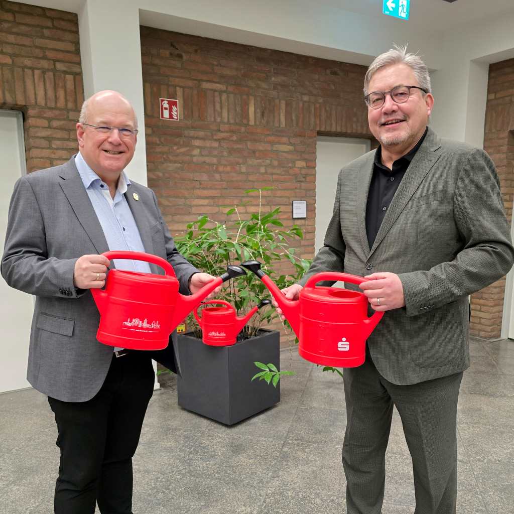 Bürgermeister Frank Peter Ullrich (l.) und der Vorstandsvorsitzende der Sparkasse Düren, Uwe Willner (r.), präsentieren die knallroten Gießkannen, die die Stadt Düren in diesem Jahr als offizielles Präsent verschenkt.