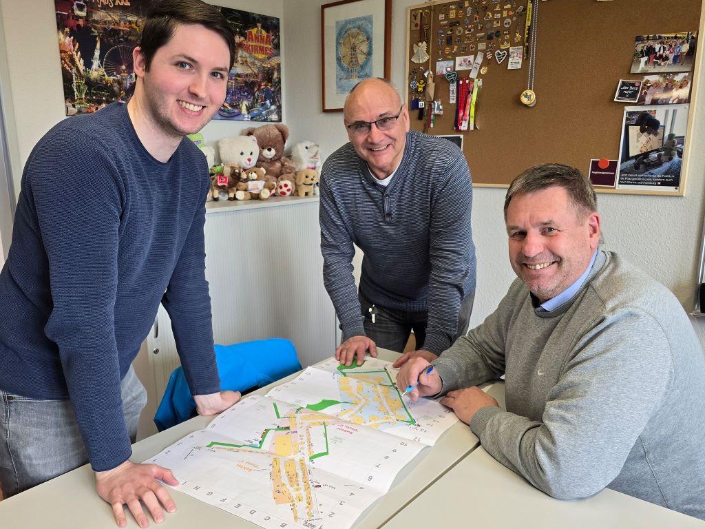 Bei Platzmeister Achim Greiff (r.), Frank Blumenthal (m.) und Mats Niederau (l.) von der Vermessungsabteilung im Amt für Stadtentwicklung laufen die Planungen für die Annakirmes 2026 auf Hochtouren. Bei Platzmeister Achim Greiff (r.), Frank Blumenthal (m.) und Mats Niederau (l.) von der Vermessungsabteilung im Amt für Stadtentwicklung laufen die Planungen für die Annakirmes 2026 auf Hochtouren.
