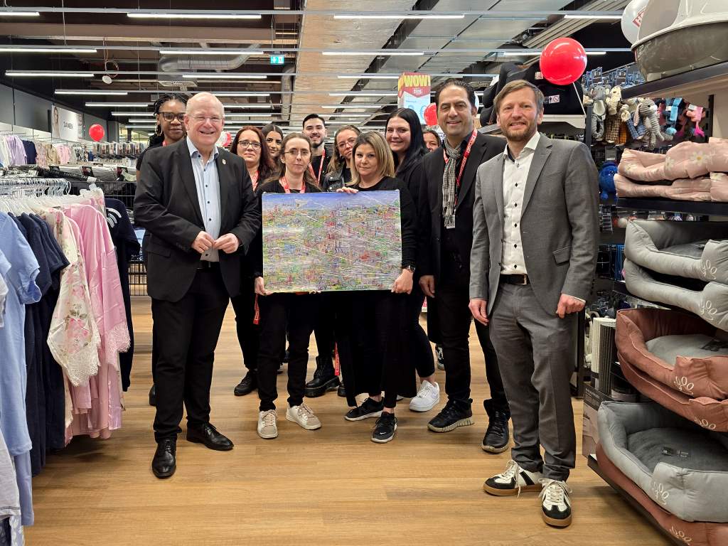 Zur Eröffnung des Woolworth-Stores überreichte Bürgermeister Frank Peter Ullrich (2.v.l.) ein Wimmelbild der Stadt Düren an das Team der Woolworth-Filiale im Stadtcenter.